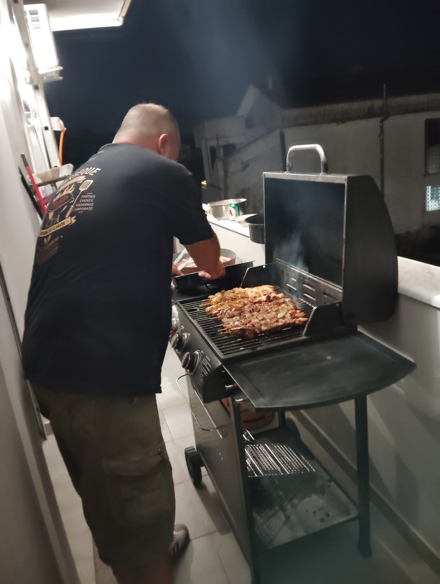 BBQ chef working a full grill of grilled meat at a private evening event