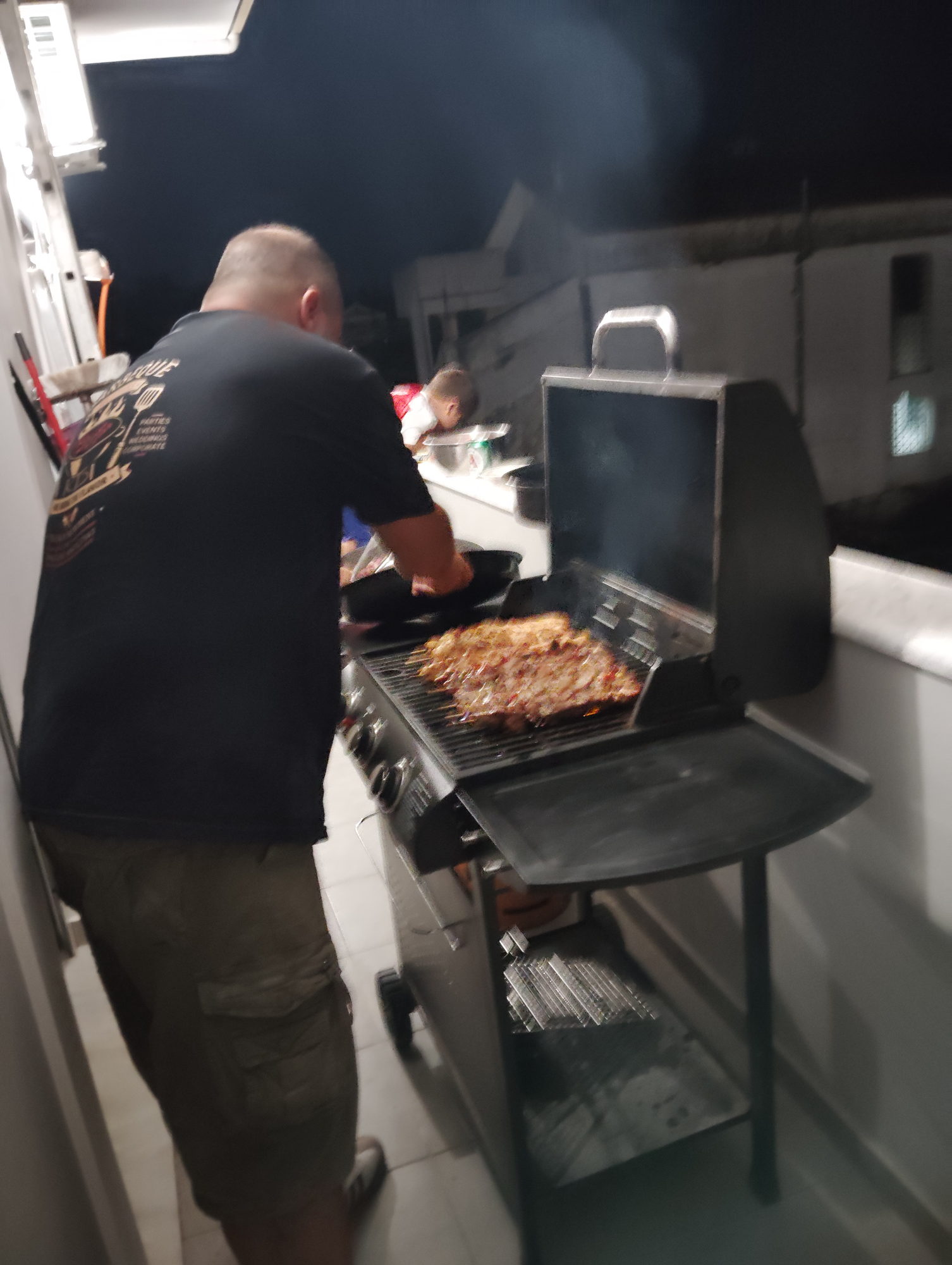 Evening barbecue service in progress, chef plating grilled meat beside the grill