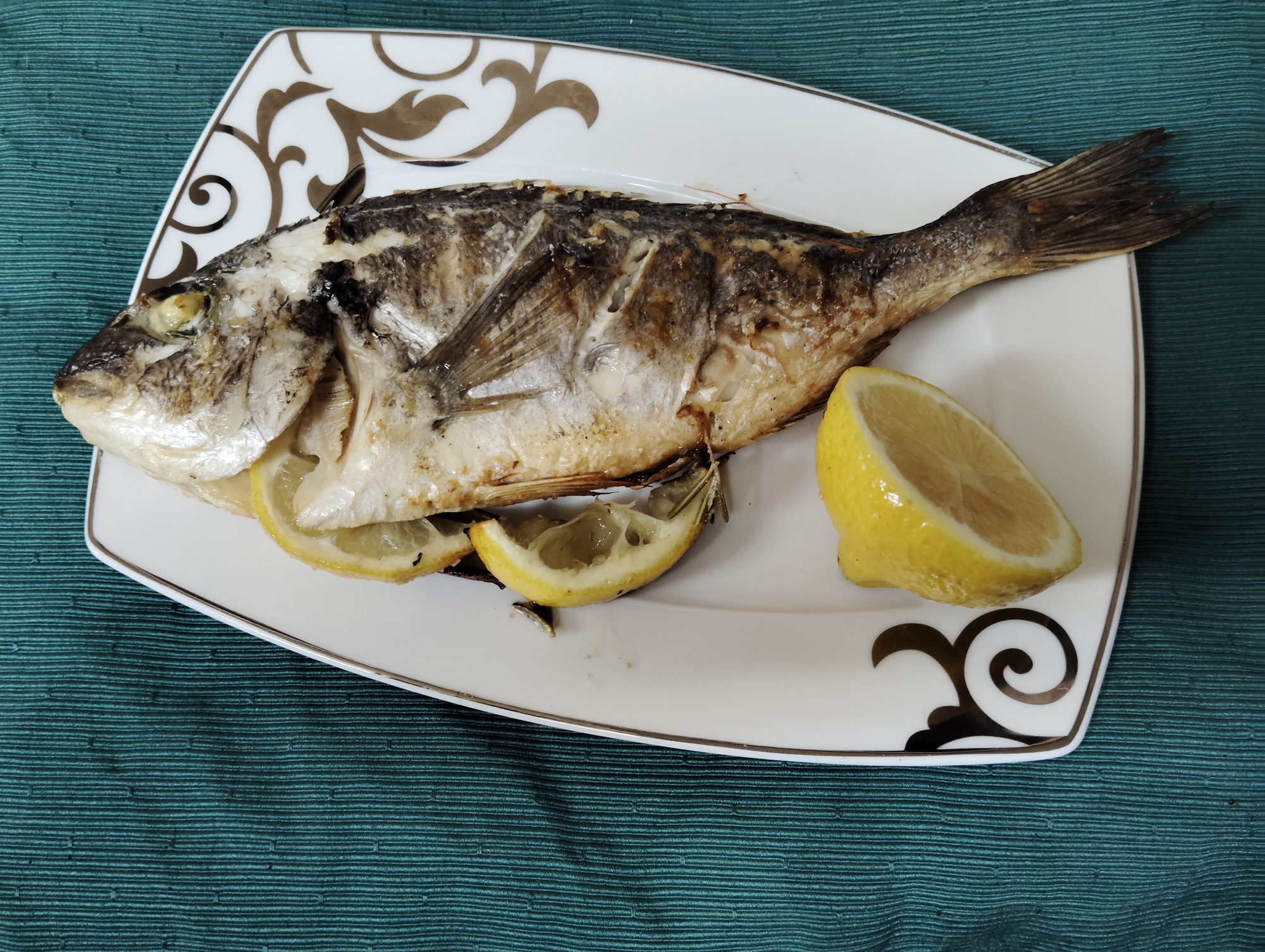 Whole grilled sea bream plated with lemon, ready to serve
