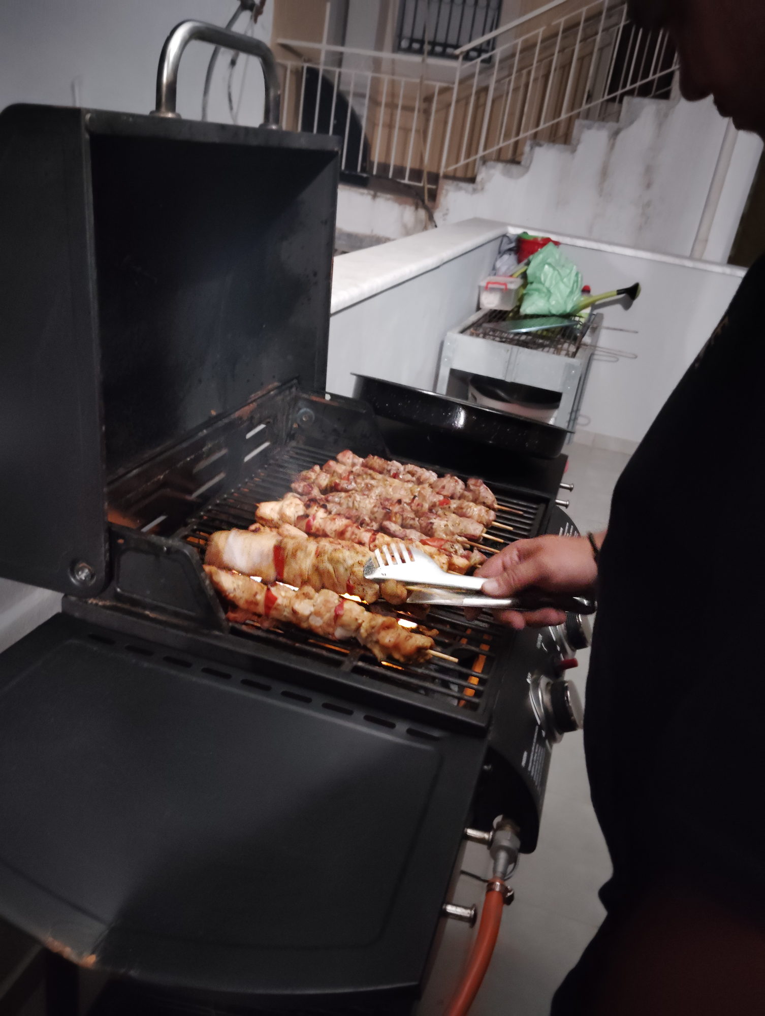 Pork and chicken souvlaki skewers cooking side by side on an open barbecue