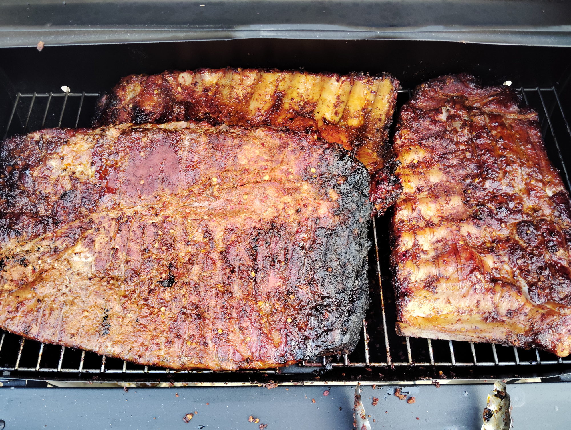 Smoked brisket and pork ribs resting on the grill grate at a private BBQ in Corfu